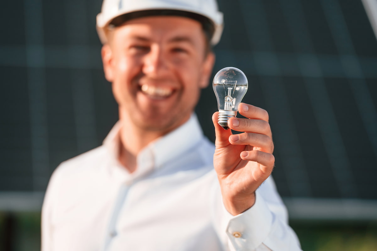 Dispositivo para ahorrar energía eléctrica - Una persona sosteniendo un foco.